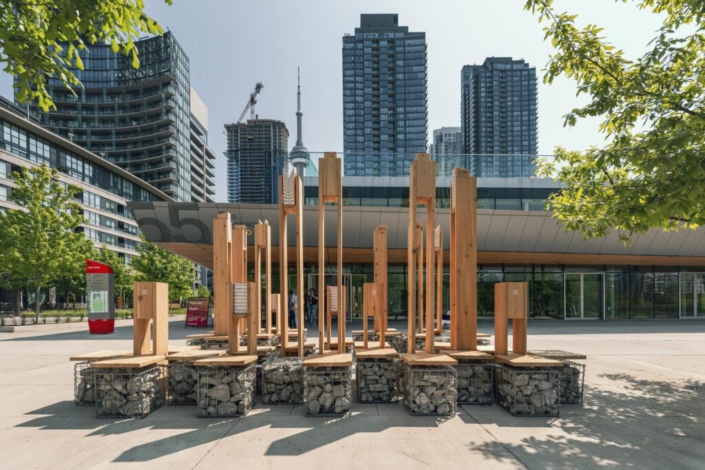 A collection of wooden seats made of wooden frames and birdhouses with steel and rock bases.