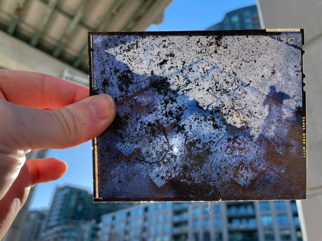 A hand holding up a film negative to the light.