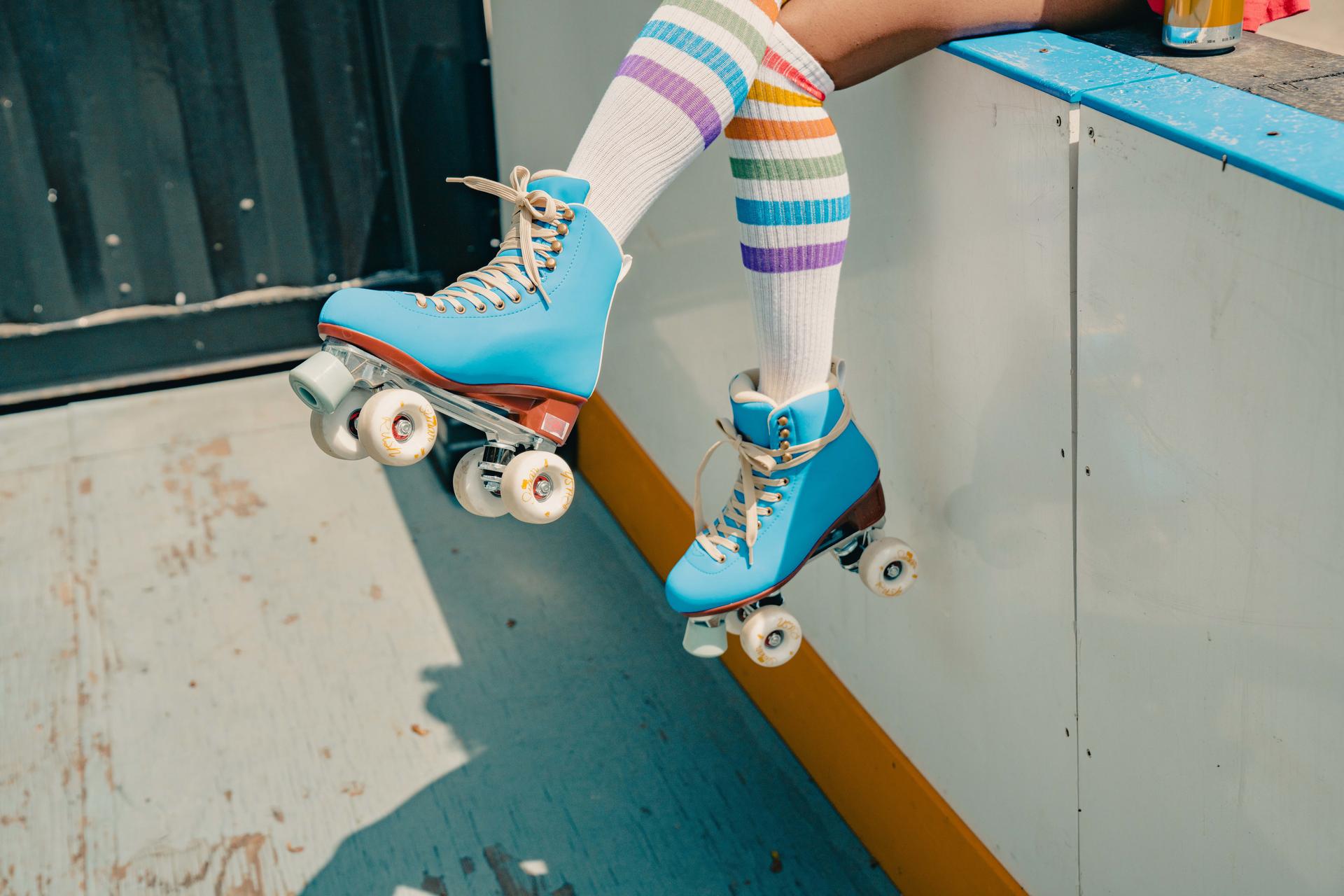 Close-up of an individual showing off a pair of blue rollerskates.