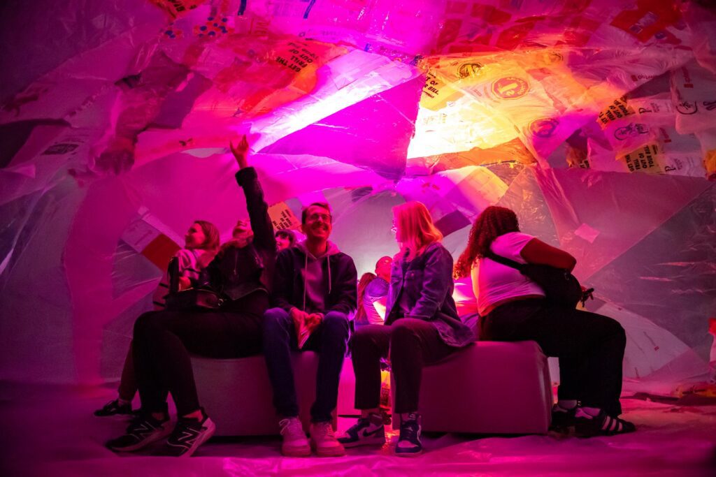 People sitting inside a giant balloon made of recycled plastic bags and waste.