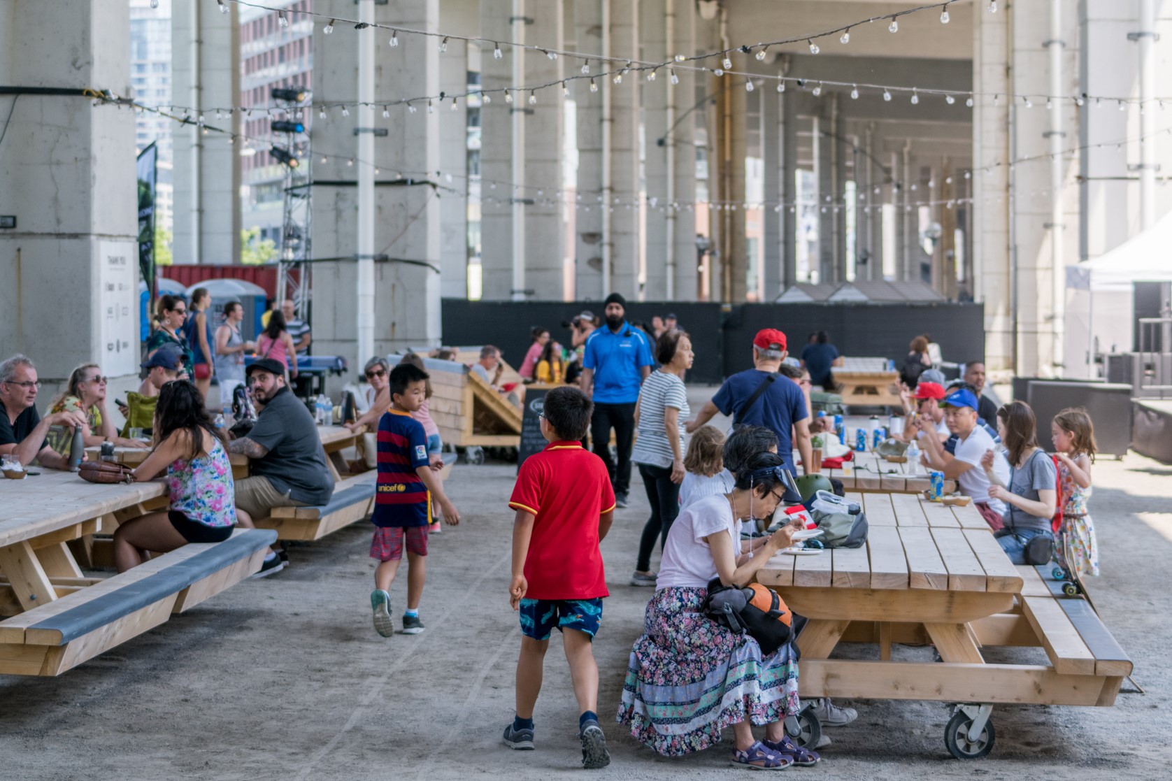 Families mingling at picnic tables under the Gardiner Expressway.