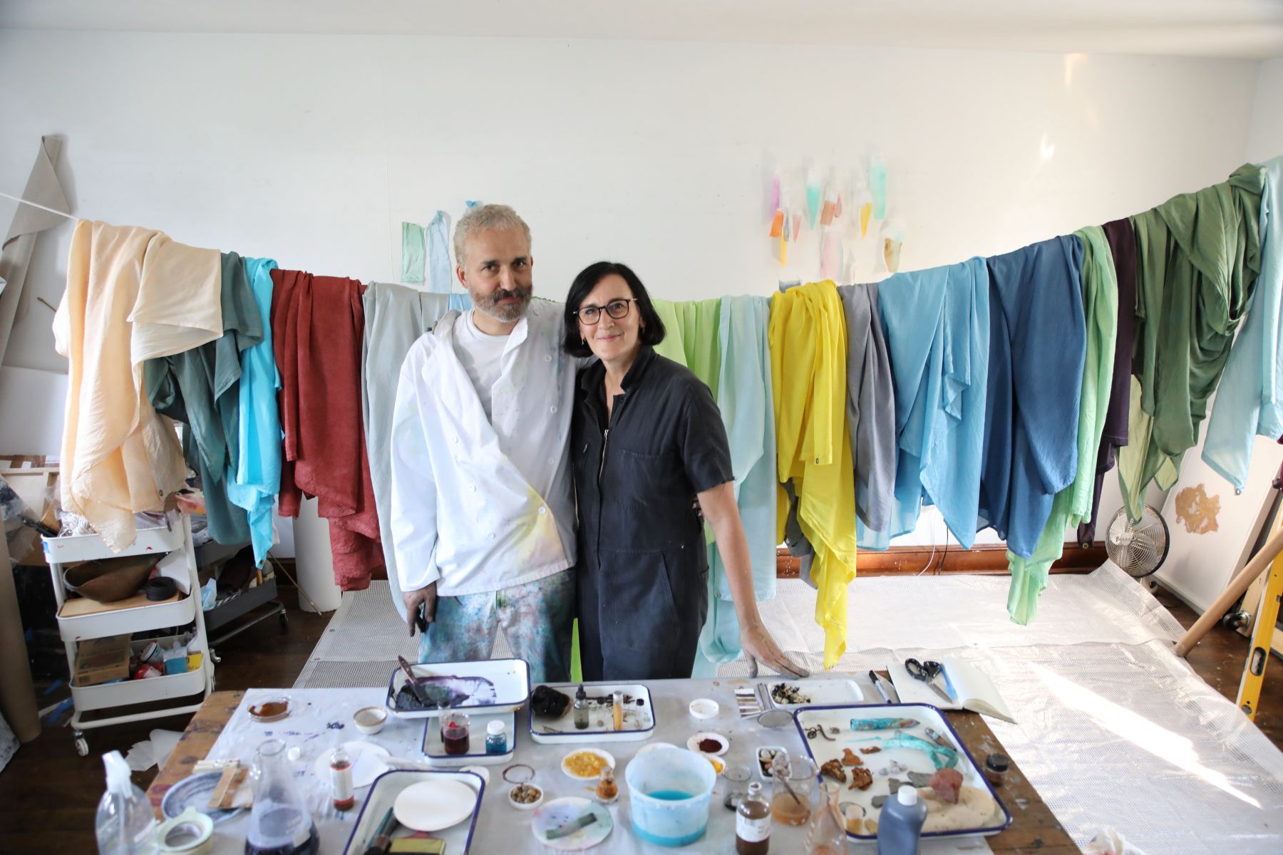 Melissa McGill and Jason Logan in art studio with dyed silk fabric for A Lake Story in the background.