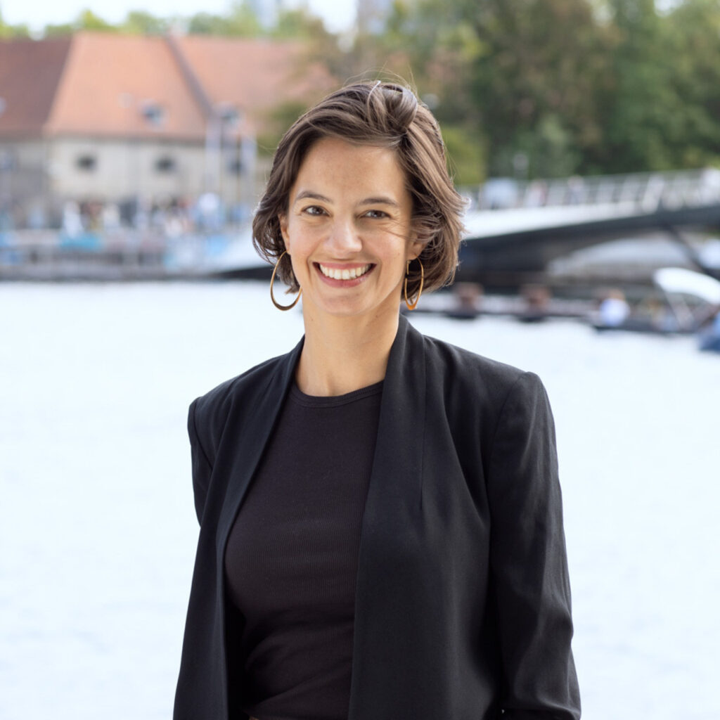 Headshot of Julia D. Day, Partner and Director of Gehl New York, with scenic waterfront view in background.