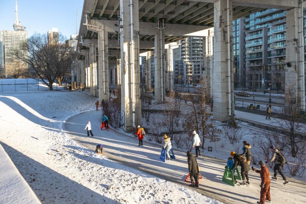 Side view of people skating on The Bentway trail