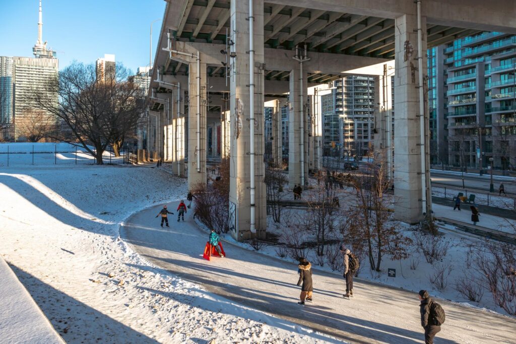People skating onTthe Bentway Skate Trail beneath the Gardiner Expressway on a snowy winter day.